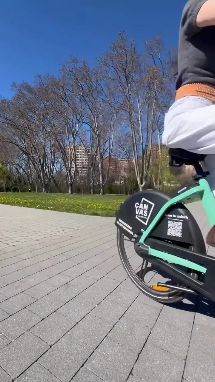Estudiante en una bici eléctrica Cityflow con la marca Canvas, por un paseo junto a un parque