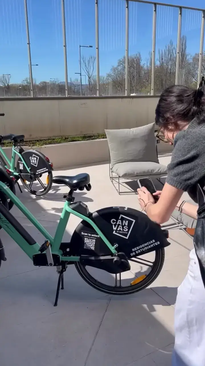 Estudiante junto a una bici eléctrica Cityflow con la marca Canvas en la terraza de la residencia